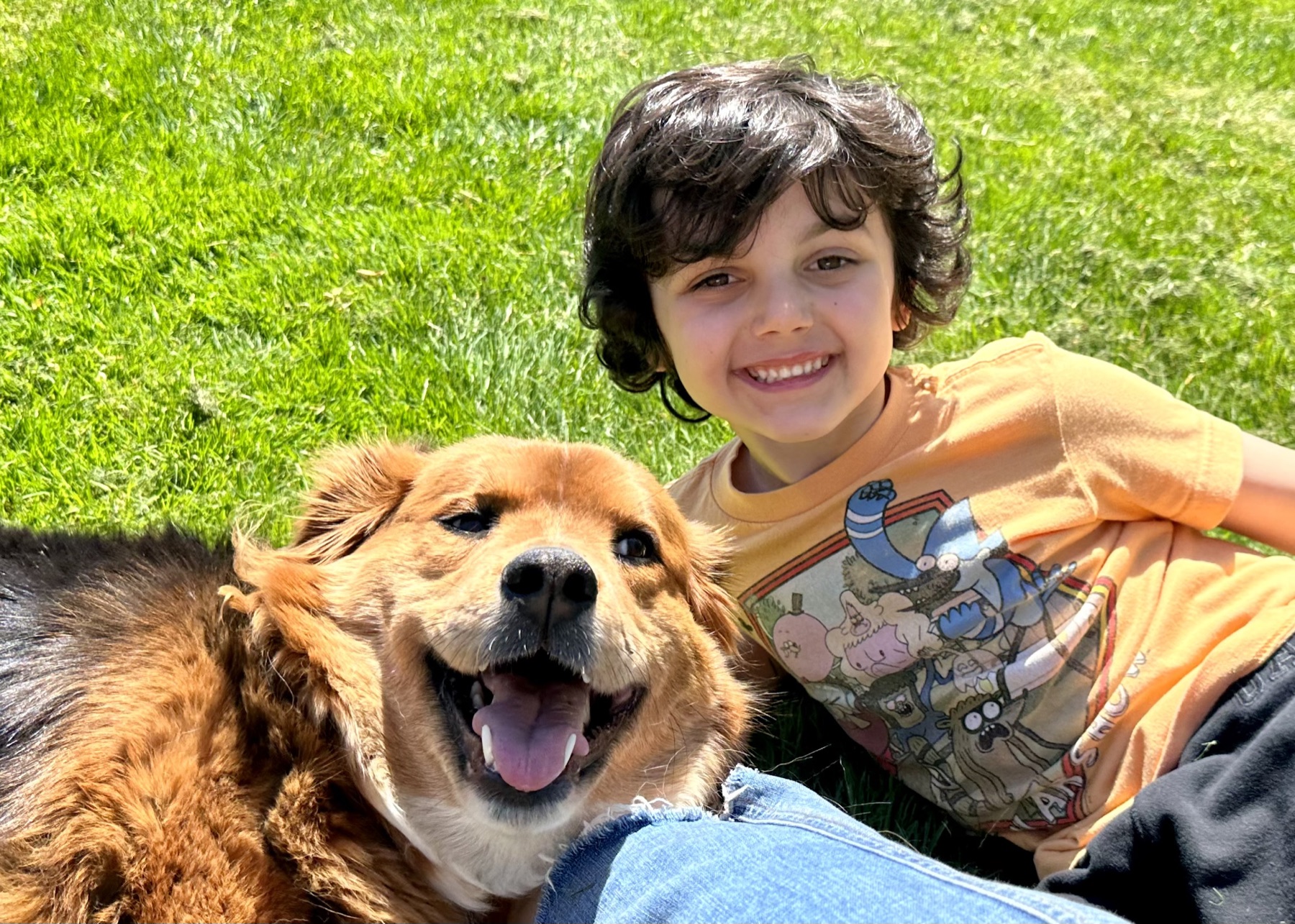 Foxy and Lukas smiling together on bright green grass